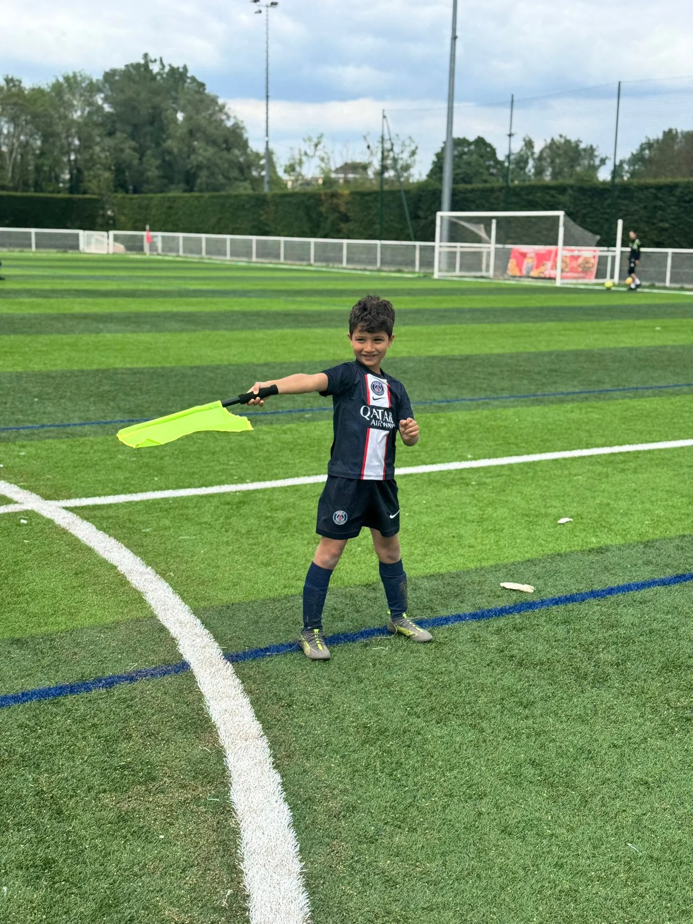 Jeune participant tenant un drapeau au bord du terrain pendant une activité collective